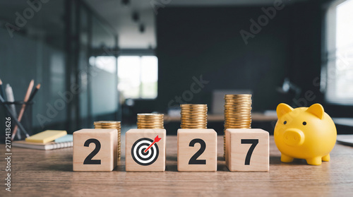 Financial goals for 2027 with wooden blocks and piggy bank concept