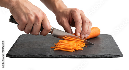 PNG cut out isolated background. A close-up shot of a person's hands using a chef knife to slice a fresh orange carrot into fine julienne strips on a dark slate cutting board.