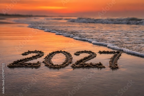 Year 2027 written on wet sea sand beach at sunset 