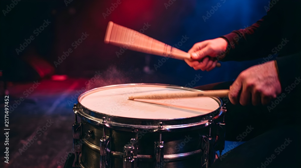 Obraz premium Drummer playing snare drum with sticks on stage with concert lighting