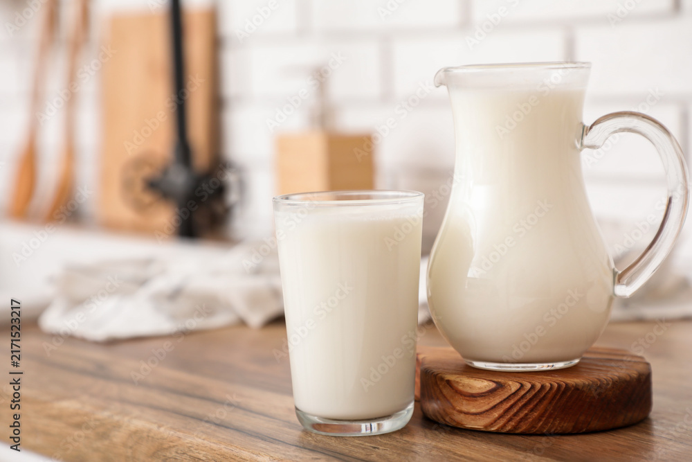 Naklejka premium Jug and glass of fresh milk on counter in kitchen