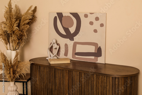 Chest of drawers, pampas grass in vases and picture near brown wall in room. Closeup