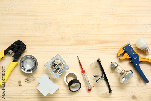Fotografie Electricians tools and light bulbs on wooden background