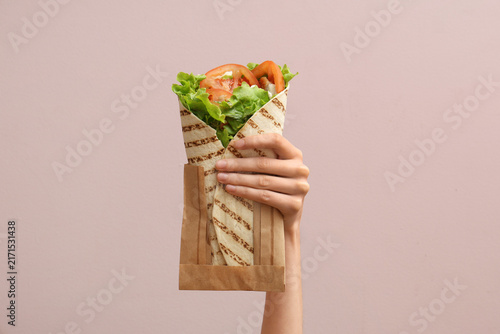 Fotografía Hand with tasty doner kebab on pink background