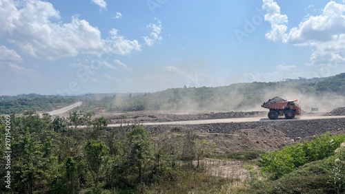 Large mining dump truck hauling materials across wide open pit mining haul road