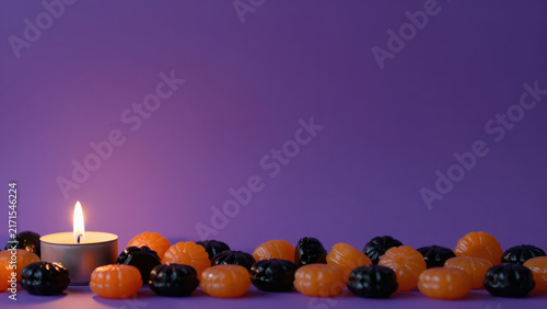 Halloween pumpkin candle flame purple background decoration autumn create mysterious festive scene, with glowing light among colorful miniature gourds and dark seasonal ornaments