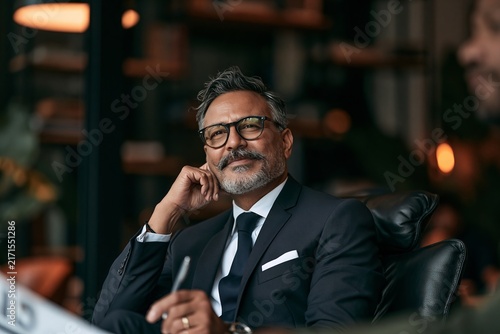 Mature businessman with beard and glasses listening attentively during a corporate meeting