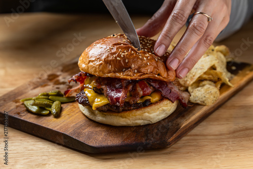 Cutting a loaded double bacon cheeseburger in half with a knife