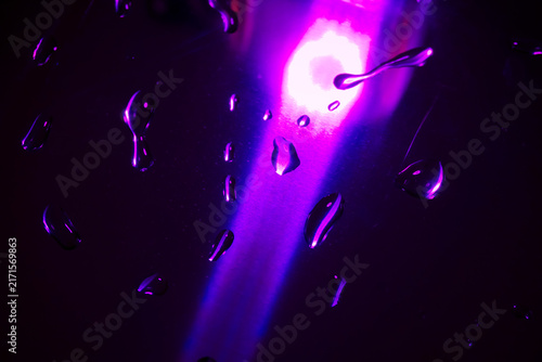 Abstract glowing neon purple water drop stream on sleek glass surface, dramatic futuristic condensation texture background.