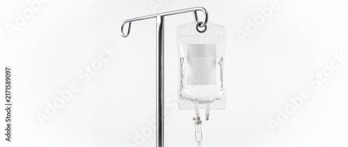 Clear intravenous drip bag with saline solution hanging on a metal medical stand in a sterile environment