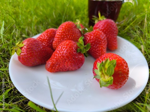 Canvastavla ripe fresh strawberries in a plate close-up on green grass background