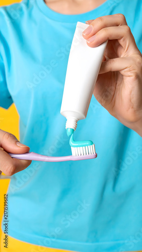 Person Applying Toothpaste on Blue and Yellow Backdrop