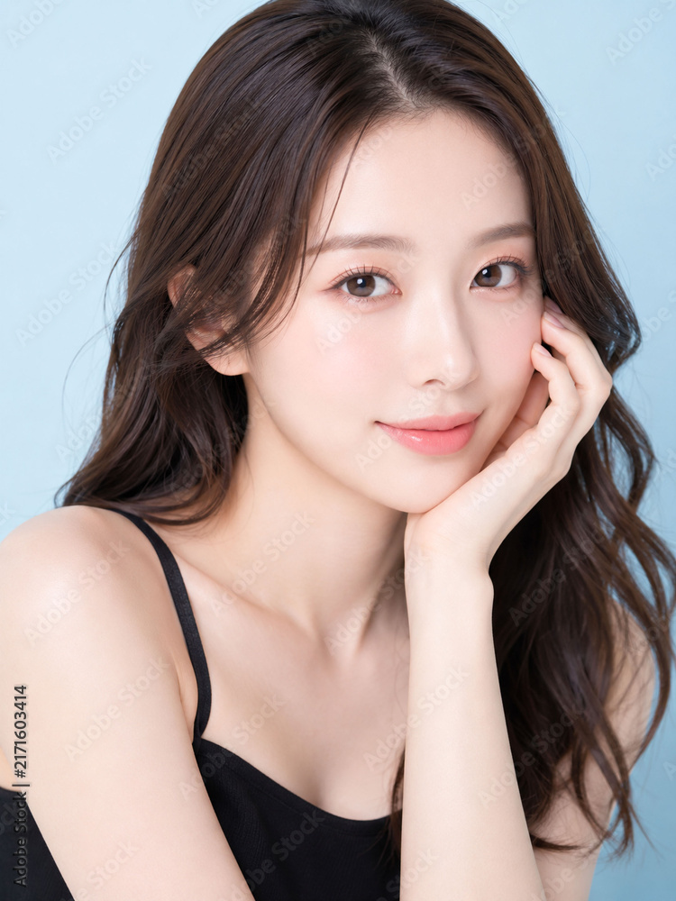 Fototapeta premium 頬に手を添えて微笑む若い日本人女性、透明感のある美肌を見せる美容ポートレート