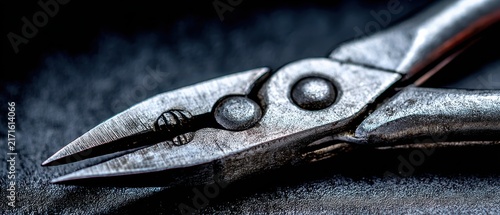 Close-up of wire cutters: A detailed close-up shot showcases the sharp jaws and metallic texture of wire cutters, set against a dark, textured background, emphasizing their industrial utility.