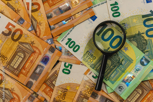 Examining euro banknotes with a magnifying glass for financial review
