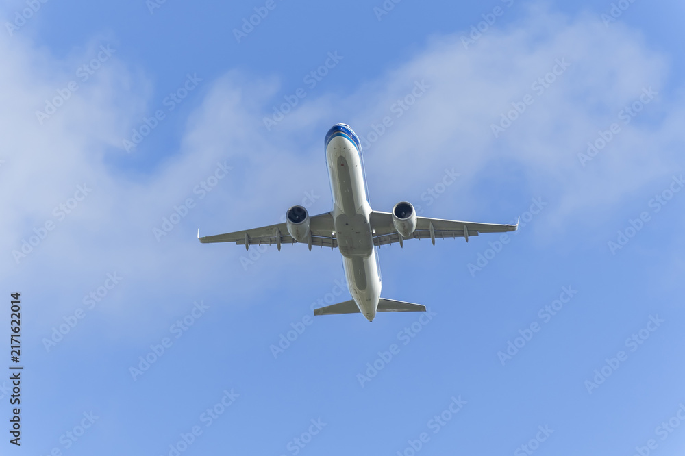 Fototapeta premium Passenger airplane flying overhead in clear blue sky