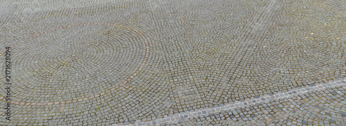 Intricate cobblestone pavement with circular patterns in a public square.