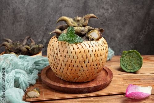 Fotografie Fresh Water Caltrop Pods in Woven Bamboo Basket on Rustic Table