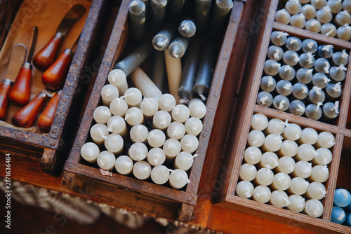 Obraz na płótnie Numerous taper candles arranged in wooden compartments with carving tools in a b