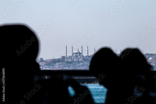 The Sultan Ahmet Mosque seen through human silhouettes. Mosques and minarets: the classic Istanbul skyline. Place of worship. Historical architectural structure. Horizontal photo.