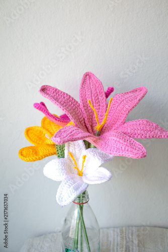 Women's labor. Handmade artificial flower. Crochet decoration. Hobby, leisure activity. Knitted flowers. Art or romantic gift concept. Needle. No people, nobody. Vertical photo.
