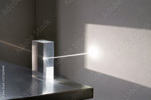 Sunbeam passing through clear acrylic block onto white wall, light transmittance concept