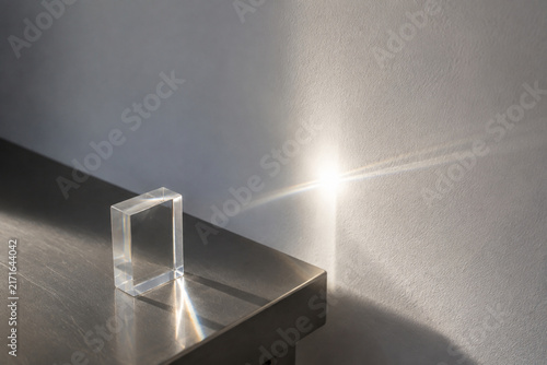 Sunbeam passing through clear acrylic block onto white wall, light transmittance concept