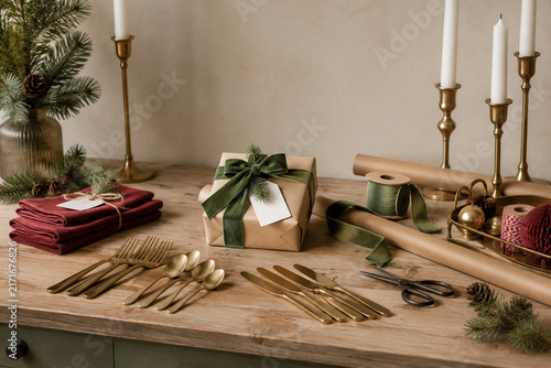 Gift wrapping station with cutlery, napkins, pine sprigs, and candles, holiday preparation concept