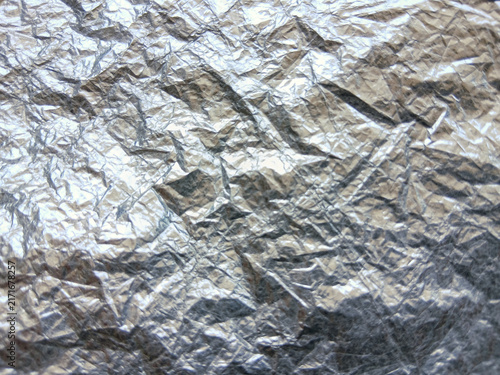 Crumpled silver foil or metallic wrapper texture background with shiny reflections