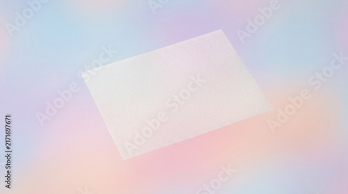 A single blank white square card rests on a diffused, colorful, and artistic backdrop.