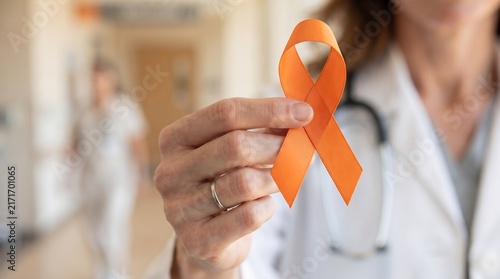 Closeup of a doctor holding an orange awareness ribbon to signify support for multiple sclerosis and selfharm prevention in a hospital setting