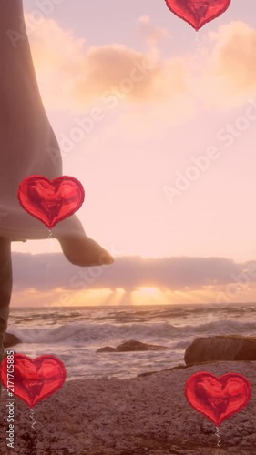 Multiple heart balloons floating against young couple embracing each other near sea shore