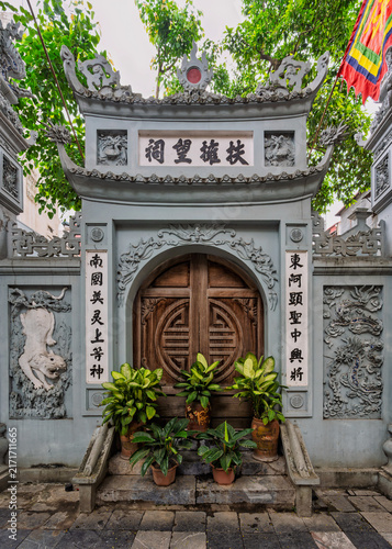 Traditional stone entrance gate with intricate relief carvings and potted plants at the historic Phu Ung Temple in Hanoi, Vietnam