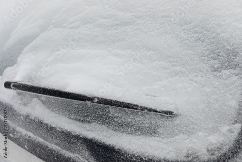 Car rear window with windscreen wipers are covered with snow after heavy winter snowfall. Natural disasters and climate change.