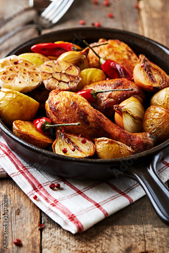 Roasted chicken wings with baked potatoes and peppers in a frying pan. 