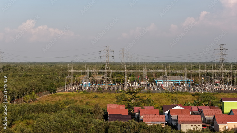 Obraz premium Electrical grid infrastructure set near a suburban area with green trees and a clear daytime sky