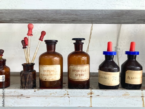 vintage amber glass pharmacy bottles and liquid droppers on a shelf