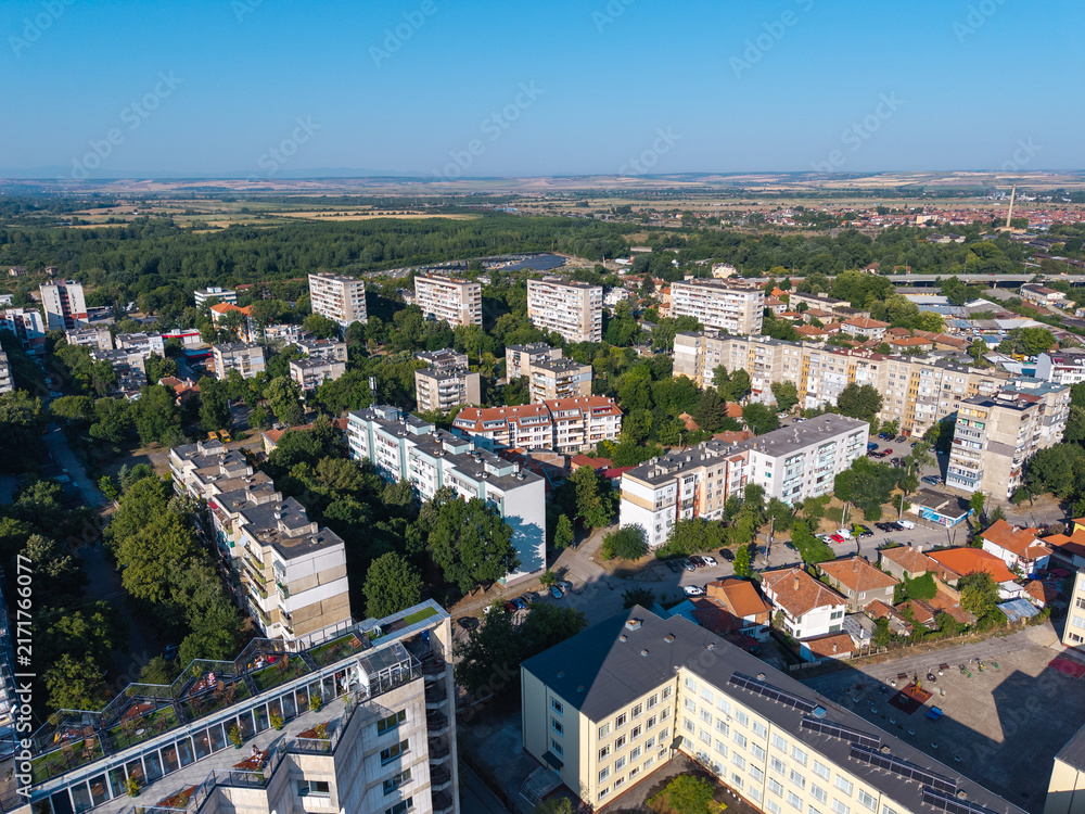 Fototapeta premium Elevated panoramic view of Vidin, Bulgaria, featuring residential apartment blocks, a tree-lined boulevard and the urban landscape extending toward the horizon on a sunny summer day. Drone view