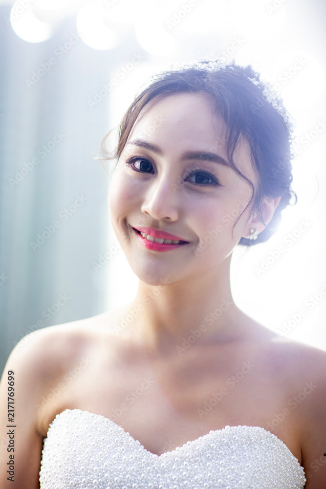 Fototapeta premium An elegant East Asian bride, dressed in a luxurious white lace long-sleeved wedding dress, was photographed up close.