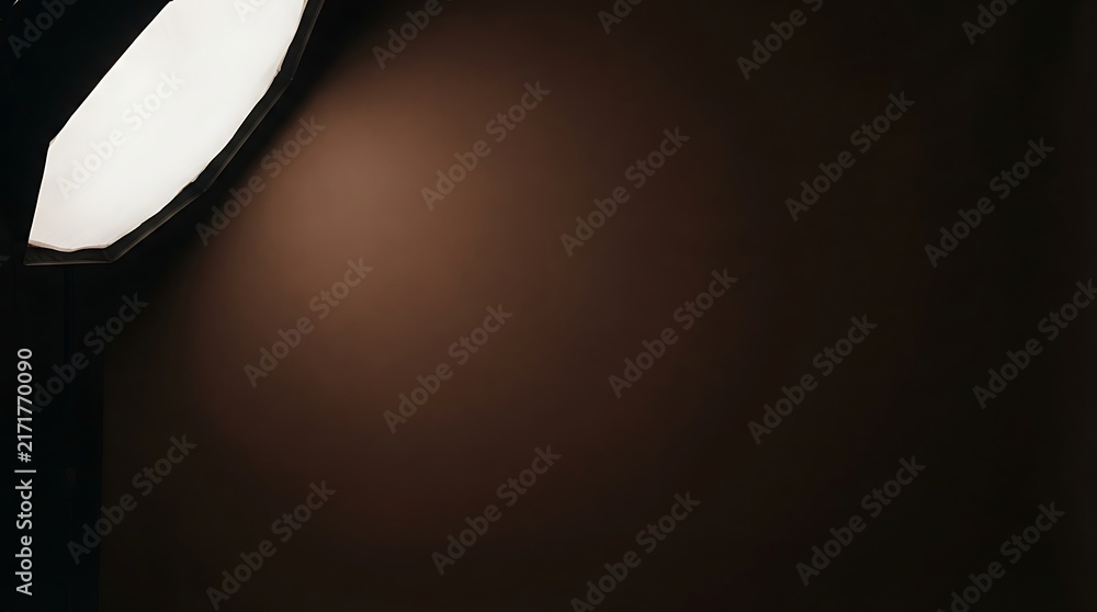 Obraz premium Professional photography softbox illuminating a dark studio background with a soft, warm light gradient.