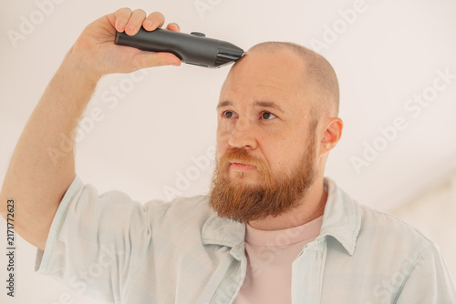 Man shaving his head and looking aside at home