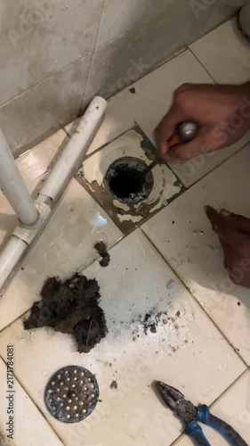 Plumber Cleaning Clogged Shower Drain Pipe with Tools
