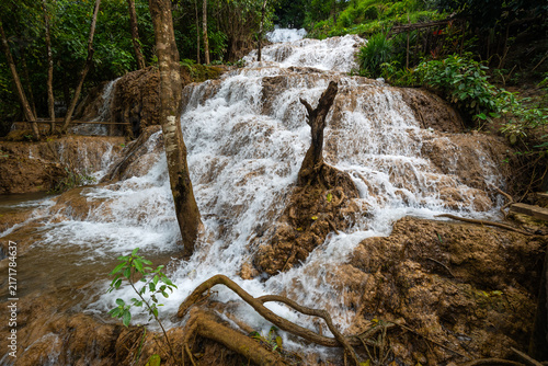 Canvastavla Scenic limestone cascading waterfall at Naw Ta or No Taw in Karen State, Myanmar, surrounded by lush green tropical forest, natural brown rock cliff, and flowing stream in bright daylight