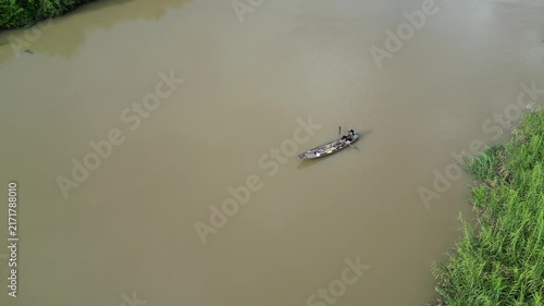 Aerial Drone Tracking a Small Boat Rowing Along a Muddy Alluvial River in Dak Lak, Vietnam, Capturing Brown Turbid Water and the Scenic Rural Landscape of Vietnam's Central Highlands