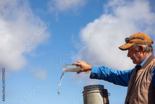 Farmer/grazier tipping water out of a rain gauge