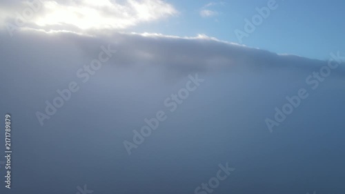 Aerial Drone Descending Slowly From Above the Clouds at Early Morning Sunrise, Capturing Soft Golden Sunlight and Gradually Entering a Bright Layer of Misty Clouds in Vietnam