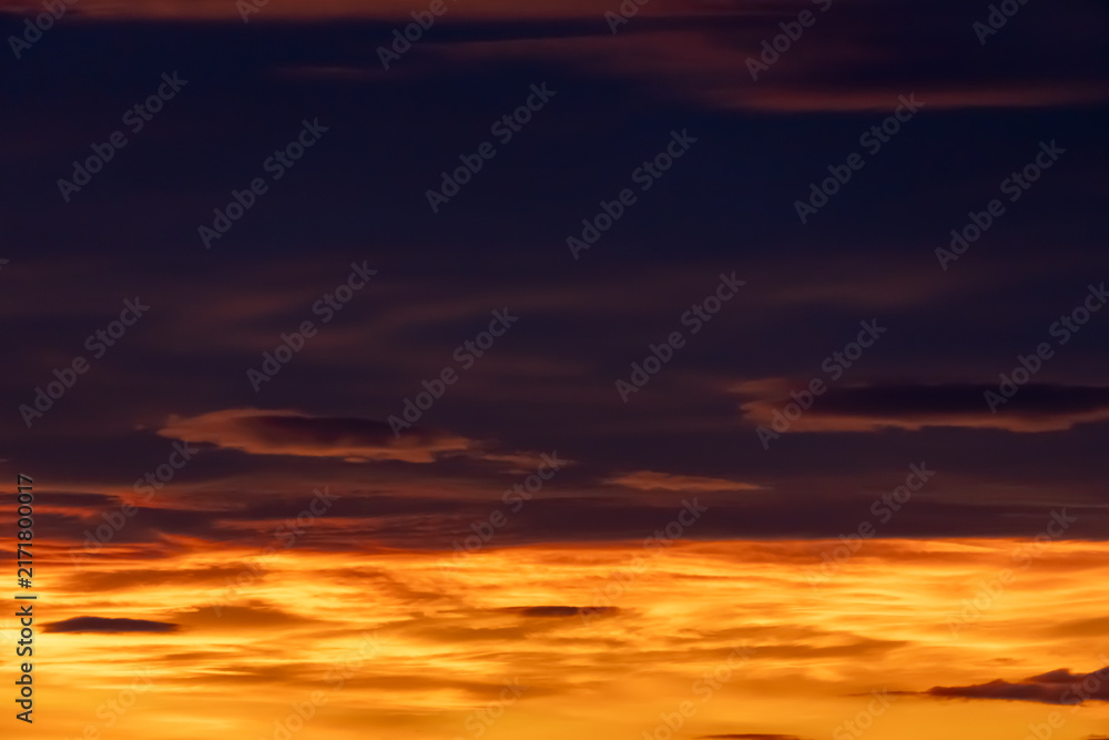 Fototapeta premium Dramatic sunset sky with glowing orange clouds and dark moody atmosphere for background