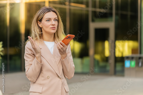 Bild auf Leinwand Young woman discussing work issue walking in city street on speakerphone with tense gestures