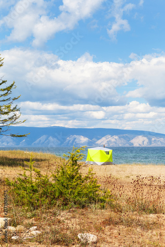 Lake Baikal in summer. Olkhon Island. A green camping tent on the sandy beach of the Small Sea on a sunny August day. Summer travel and outdoor recreation