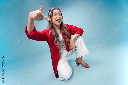 Cute young Indonesian woman is sitting on the floor and pointing to the copy space below.